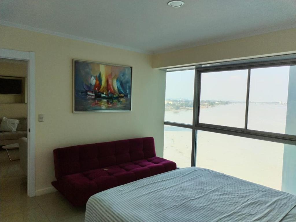 a bedroom with a bed and a couch in front of a window at Room with a view in Guayaquil