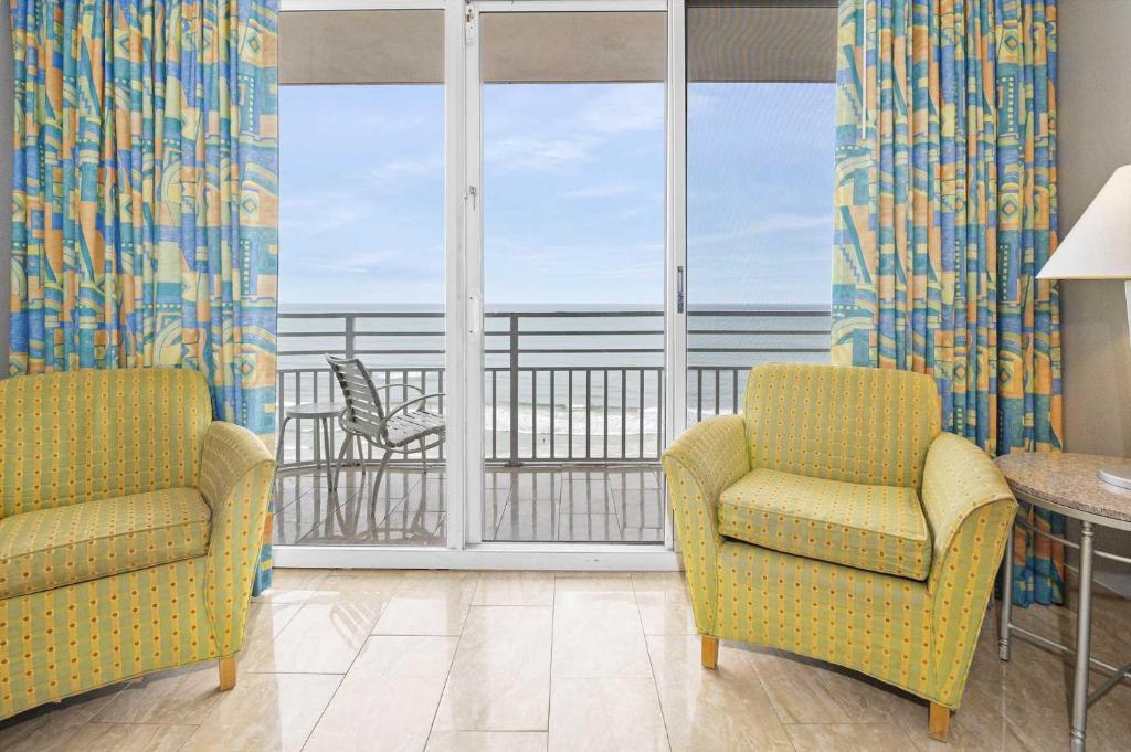 sala de estar con 2 sillas y balcón en Luxury Beach Villa Ocean Walk Resort Daytona Beach, en Daytona Beach
