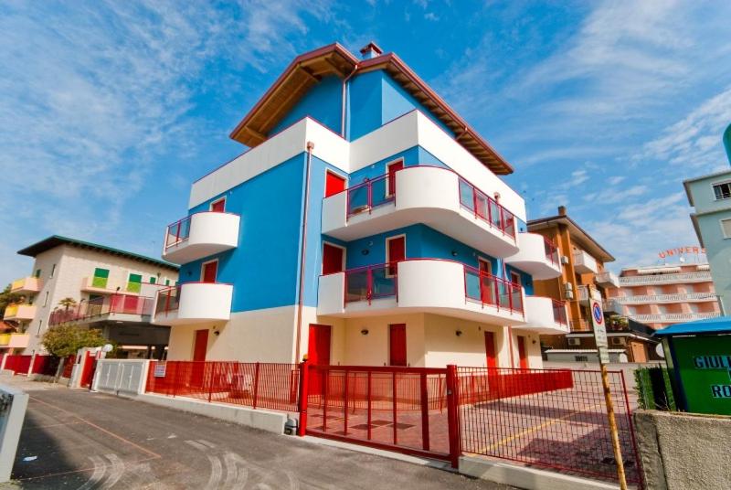 a blue and white building with a red fence at Residence Al Mare - Monolocale con Terrazza - Agenzia Cocal in Caorle