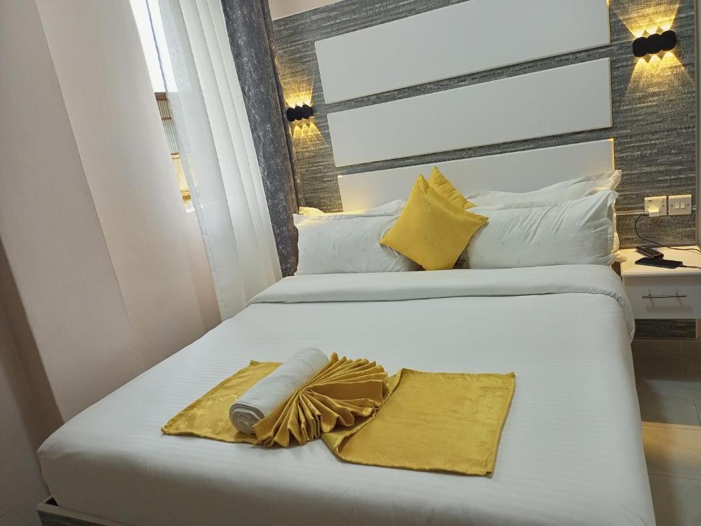 two beds with yellow and white pillows and towels at Mt. Everest Hotel in Kisii
