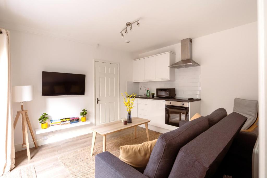 a living room with a couch and a kitchen at Guildford Town Centre with Parking in Guildford