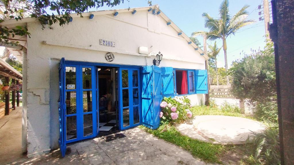 a blue door on a white building with palm trees at Hostel Casa do Bolaxa in Rio Grande