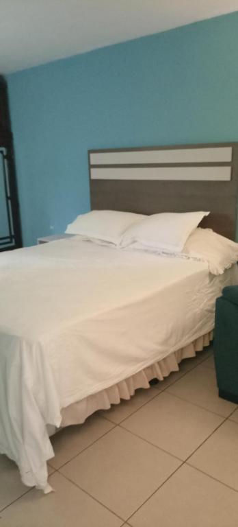 un grande letto bianco in una stanza con una parete blu di Habitación cómoda a Villa Nueva