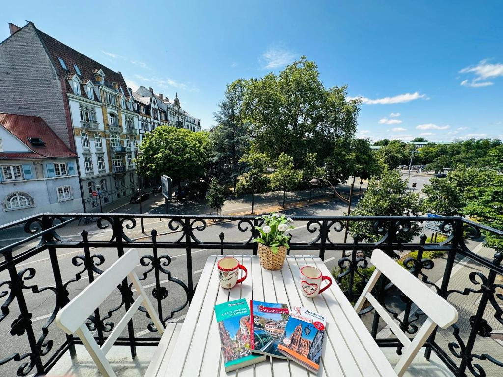 - un balcon avec une table et un livre dans l'établissement 4 étoiles Magnifique Neustadt - Spacieux, Central & Élégant avec balcon et belle vue, à Strasbourg