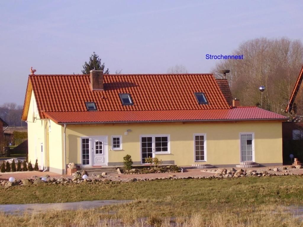 una casa con techo naranja con aves delante en Gäste-Zimmer am Elberadweg, en Damnatz