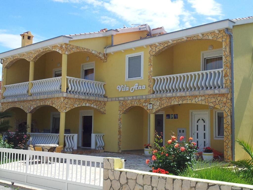 a yellow house with a white fence in front of it at Apartments Vila Ana in Vir