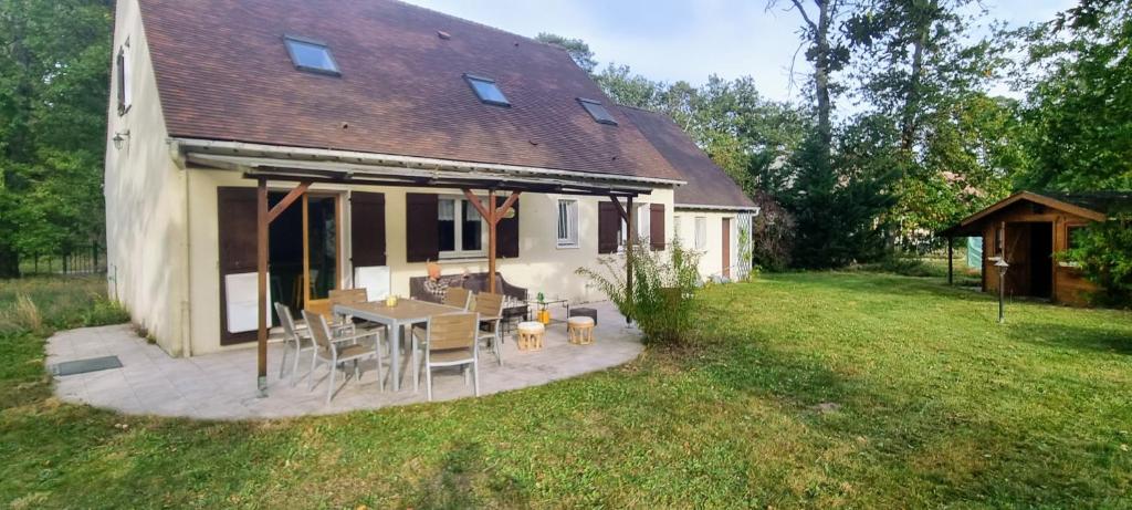 a house with a table and chairs in a yard at La maison du Diplo : Forêt, sentiers et grimpe in Le Vaudoué