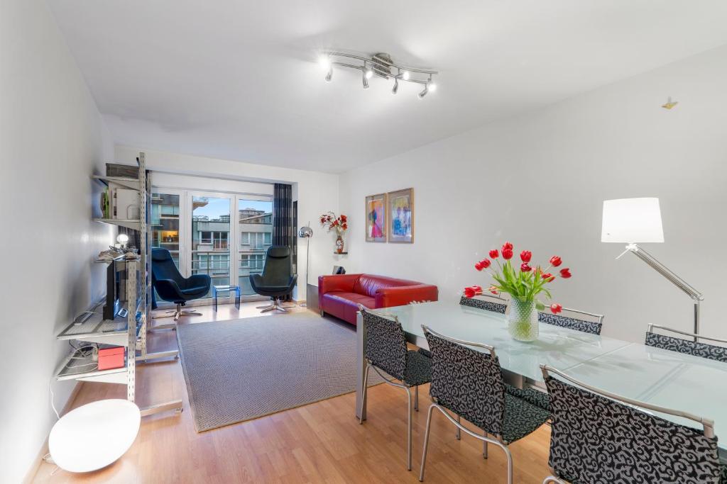 Appartement aan Zee Oostende في أوستند: غرفة معيشة مع طاولة وأريكة حمراء