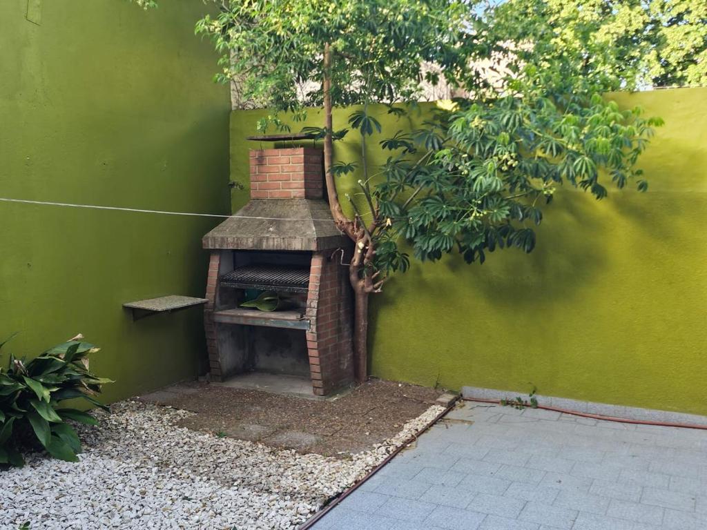 piec ceglany w zielonej ścianie z drzewem w obiekcie Malvinas casa w mieście La Plata