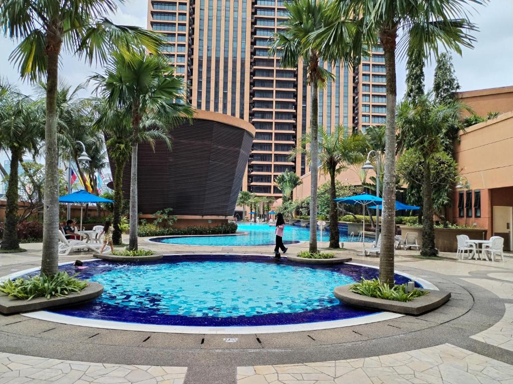 uma pessoa a caminhar em frente a uma piscina com palmeiras em Times Square Hotel Service Suite KL em Kuala Lumpur