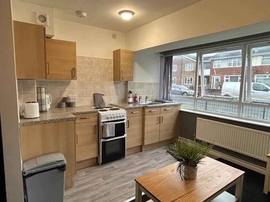 een keuken met houten kasten en een tafel en een raam bij Two bedroom apartment room 18 in Stockton-on-Tees