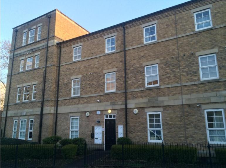 a brick building with a door in front of it at Maple Apartments in Stanley