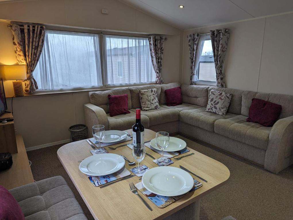 a living room with a table and a couch at Seasons Caravan 3 bedroom Haven Littlesea in Weymouth
