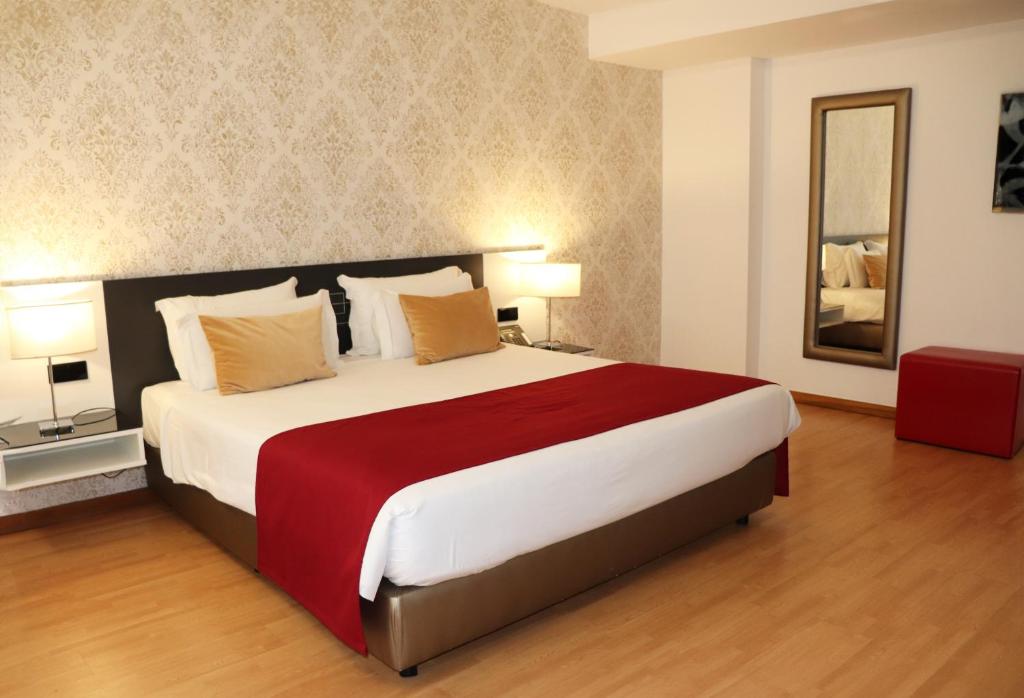 um quarto com uma cama grande e um espelho em Urban Hotel Amadeos em Matosinhos