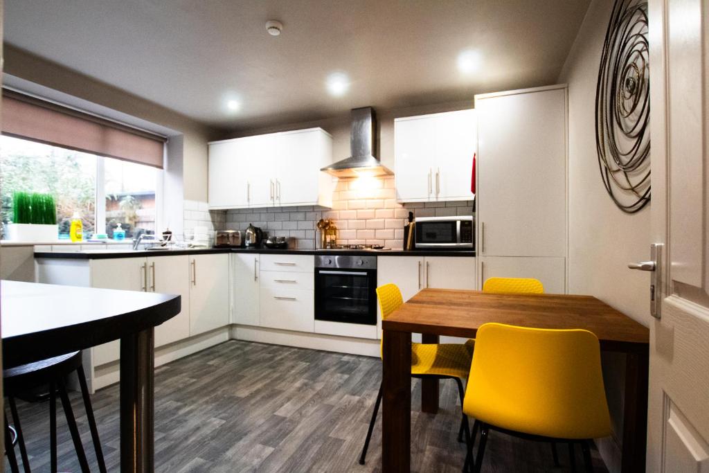 cocina con mesa de madera y sillas amarillas en Brattan House Oxton Wirral 5 bedroom 3 bathroom with on-street parking ideal for vans by Rework Accommodation, en Birkenhead