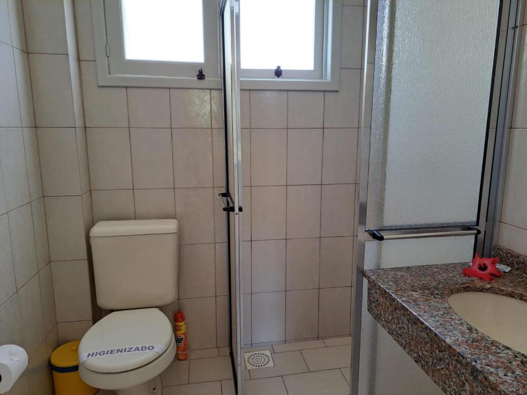 a bathroom with a toilet and a sink and a window at Velho Estaleiro Apartamentos por Temporada in São Lourenço do Sul