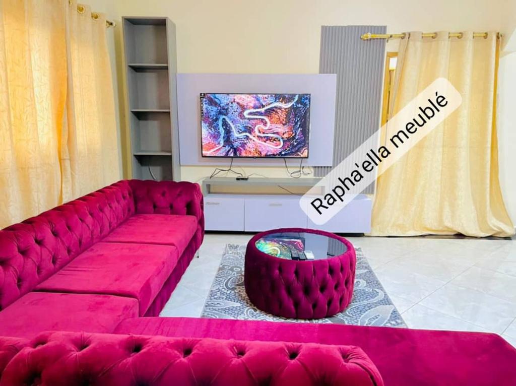 a living room with a red couch and a tv at Appartement Rapha'ella Meublé in Yaoundé