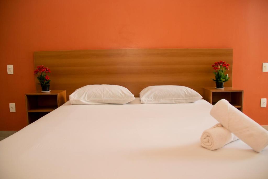 a bedroom with a white bed with two towels on it at Motel Malibu in Divinópolis