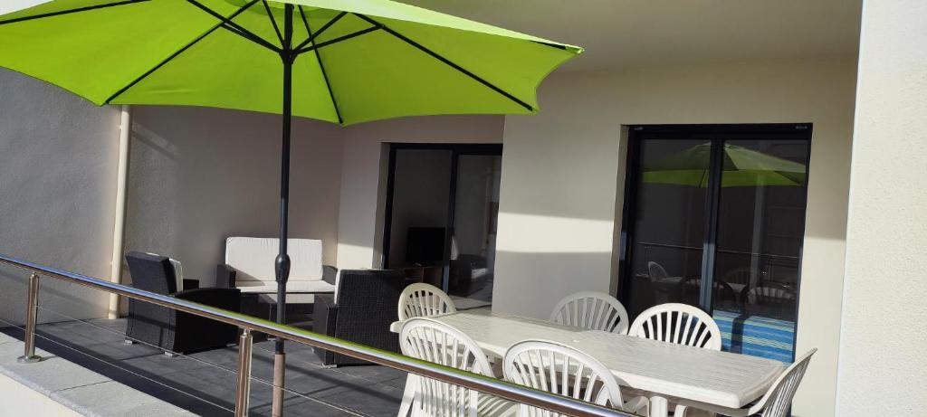 d'une table, de chaises et d'un parasol vert sur le balcon. dans l'établissement Grand T2 neuf classé 3 étoiles, à Porticcio