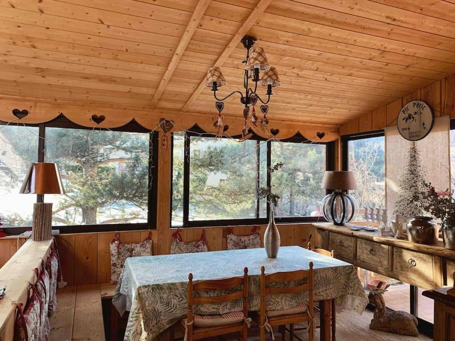 a dining room with a table and some windows at Aux trois marmottes - Chalet au pied des pistes in Formiguères