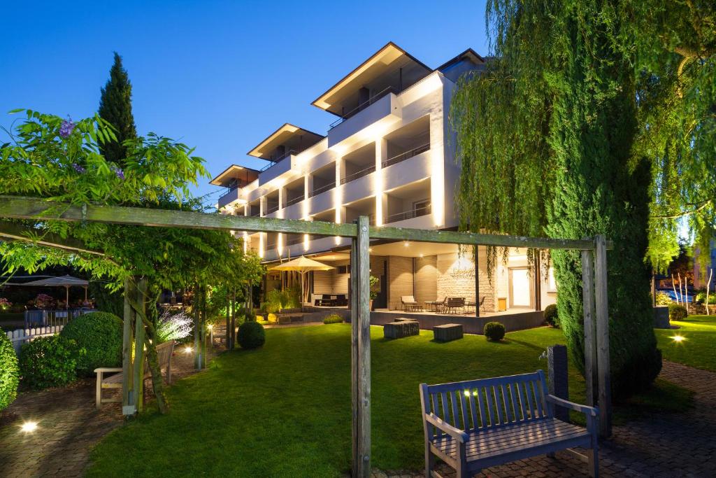 ein Gebäude mit einem Garten mit einer Bank davor in der Unterkunft Hotel Seehof in Immenstaad am Bodensee