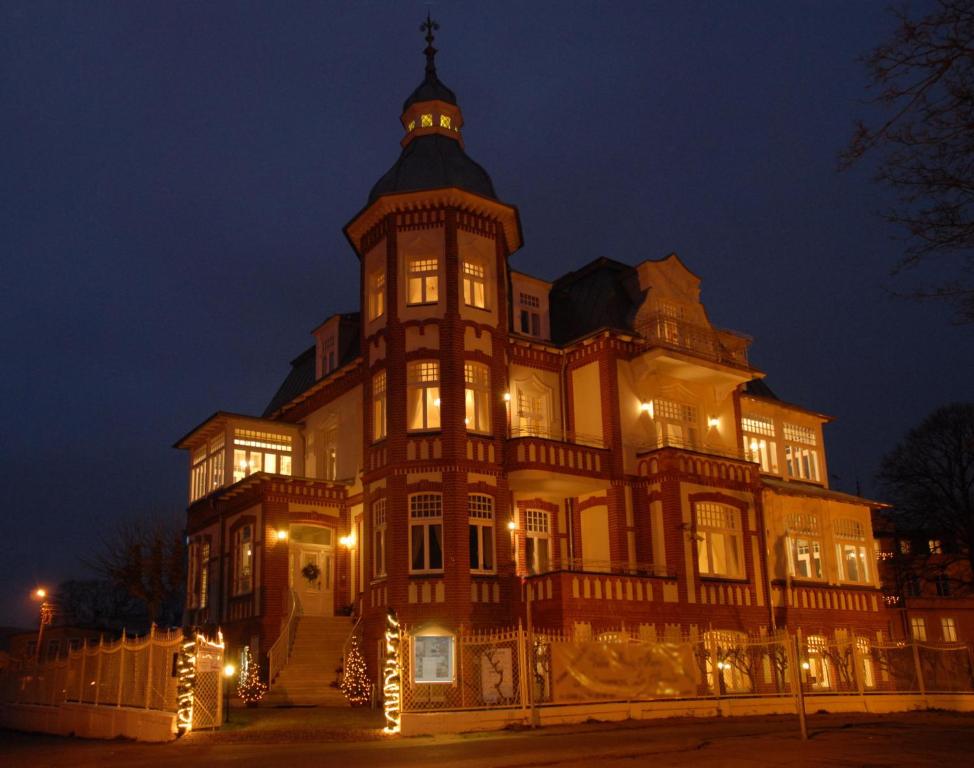 un gran edificio con una torre de reloj por la noche en Villa Stella Maris, en Międzyzdroje