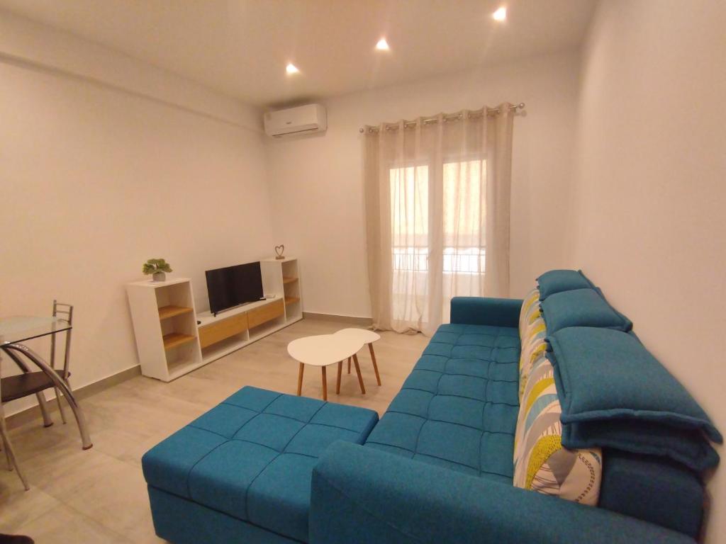 a living room with a blue couch and a tv at PortoHeli Matilda`s house 2 in Porto Heli