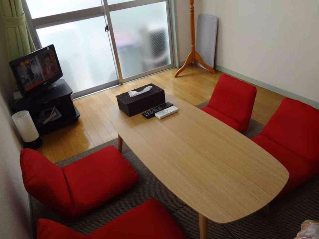 um quarto com uma mesa de madeira e cadeiras vermelhas em Vintage III - Vacation STAY 14906 em Fukuoka