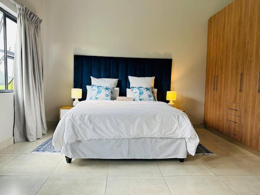 Schlafzimmer mit einem großen Bett mit blauem Kopfteil in der Unterkunft Ekhaya Luxury Apartment in Lobamba