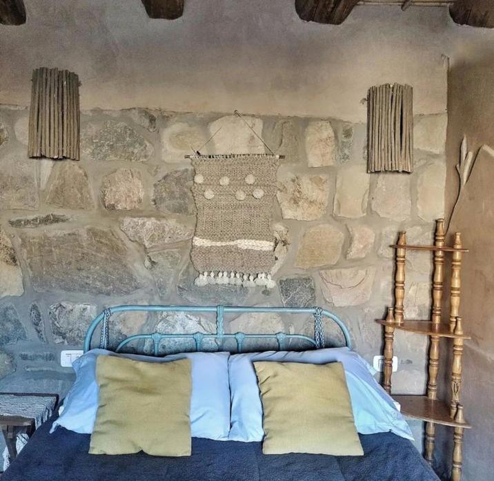 a bedroom with a stone wall with a bed at El Cerrito in Maimará