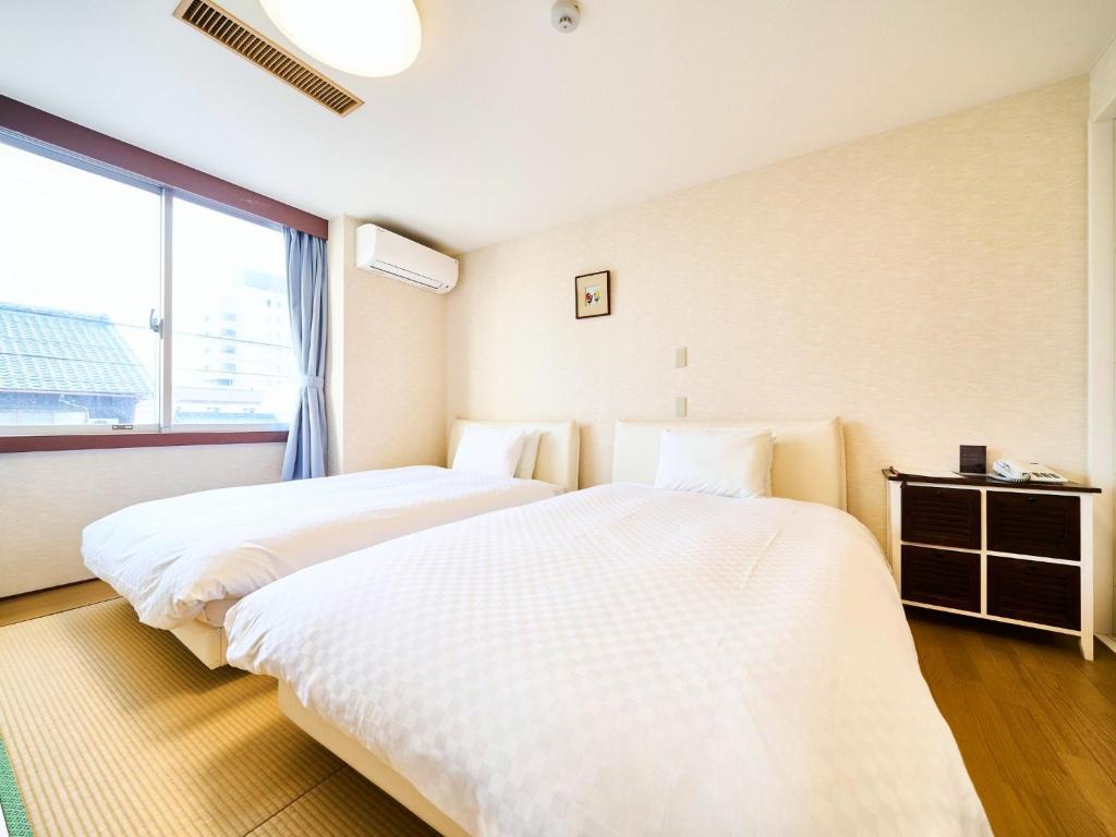 two beds in a room with a large window at Okasan Hotel - Vacation STAY 45146v in Ogaki