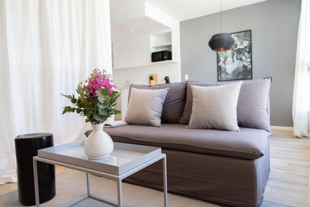 een woonkamer met een bank en een vaas met bloemen op een tafel bij Enebro Beautiful Apartment in Buenos Aires