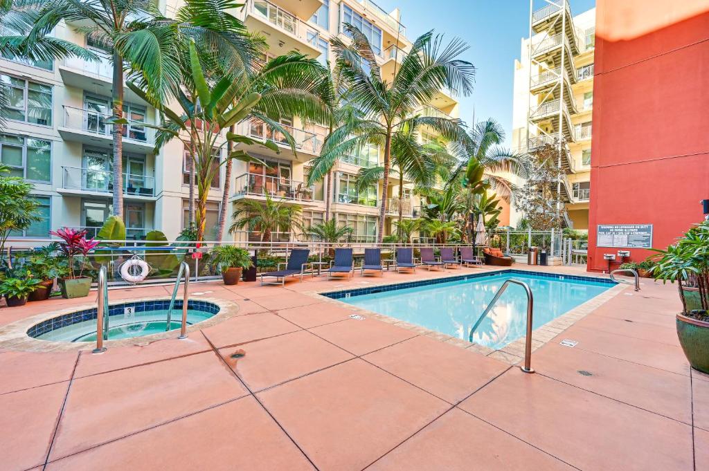 a pool in the courtyard of a apartment building with palm trees at High-End San Diego Condo with Pool and Rooftop Access in San Diego