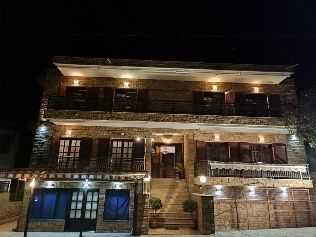 ein Backsteingebäude mit Balkon in der Nacht in der Unterkunft Ξενώνας Φωτεινη in Ouranoupoli