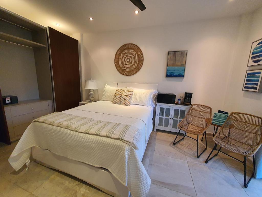 a bedroom with a large bed and two chairs at Las Palmas Joliet in Roatán