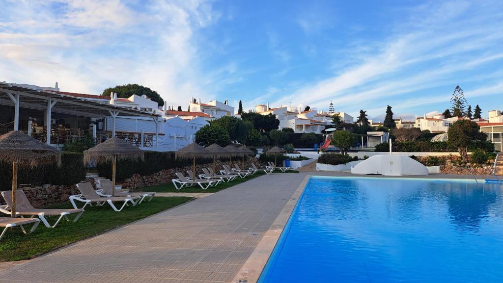 a resort with a swimming pool and chairs and buildings at Casa da Rocha in Armação de Pêra