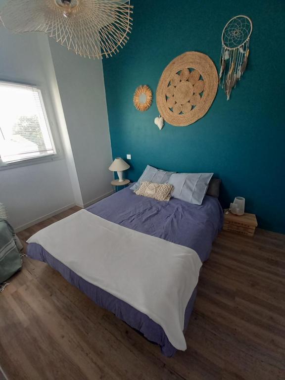 a bedroom with a large bed with a blue wall at La désirée à Noirmoutier in Noirmoutier-en-l'lle