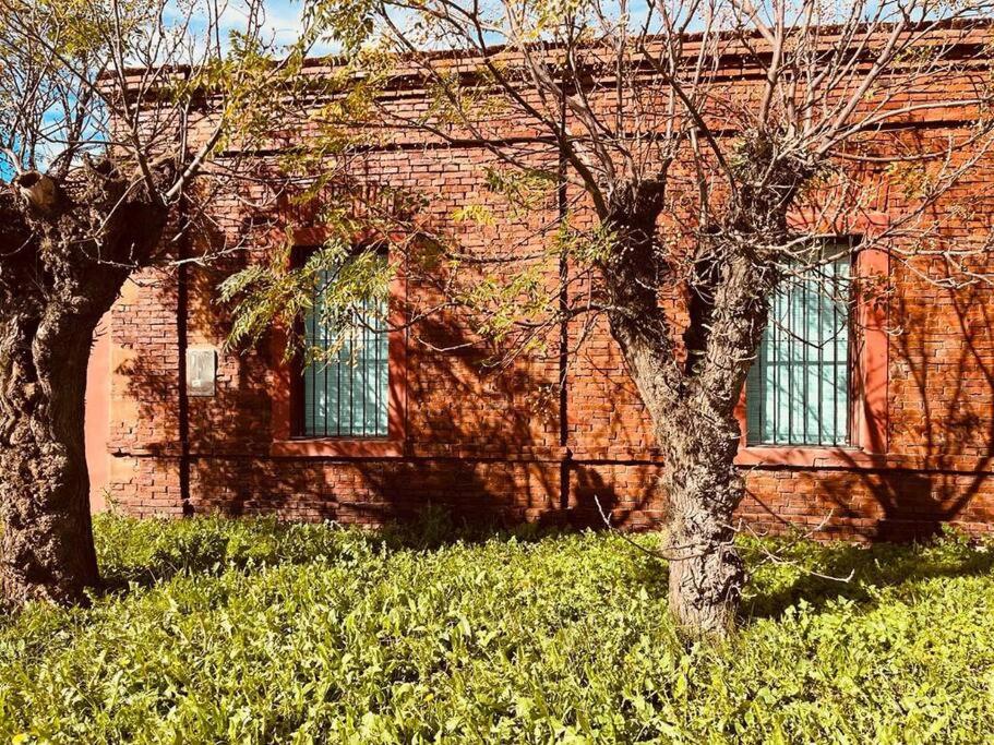 due alberi di fronte a un edificio di mattoni di El Cencerro - Casa de Campo a Villa Lía
