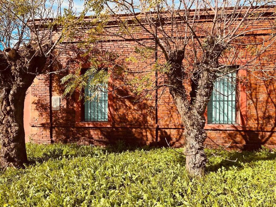 two trees in front of a brick building at El Cencerro - Casa de Campo in Villa Lía