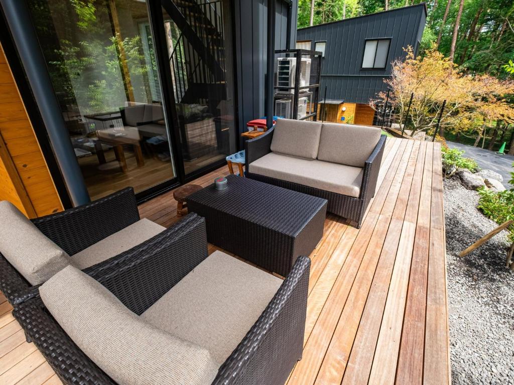 un patio con 2 sillas de mimbre y una mesa en FJ Forest - Vacation STAY 37809v, en Fujikawaguchiko