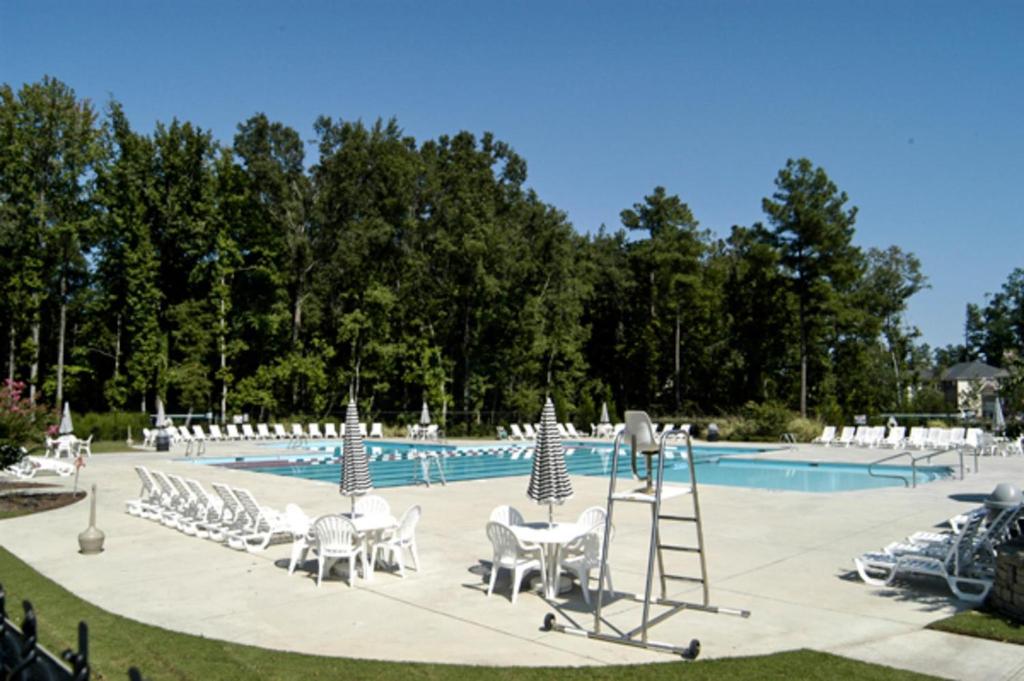 a pool with a bunch of lawn chairs and a ladder at Chiky Sanctuary in Raleigh