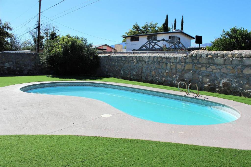 a swimming pool in a yard next to a stone wall at El Chuco Home W Pool, Pool Table,15 Min Downtown in El Paso