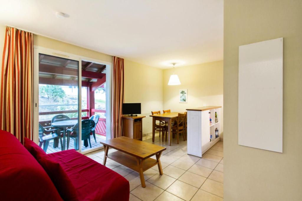 un salon avec un canapé rouge et une table dans l'établissement Village Moliets - maeva Home - Appartement 2 pièces 4 personnes Confort MAE-3029, à Moliets-et-Maa