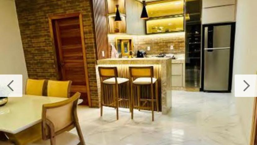 a kitchen with a bar with stools and a table at Casa Parque Minas in Córguinho