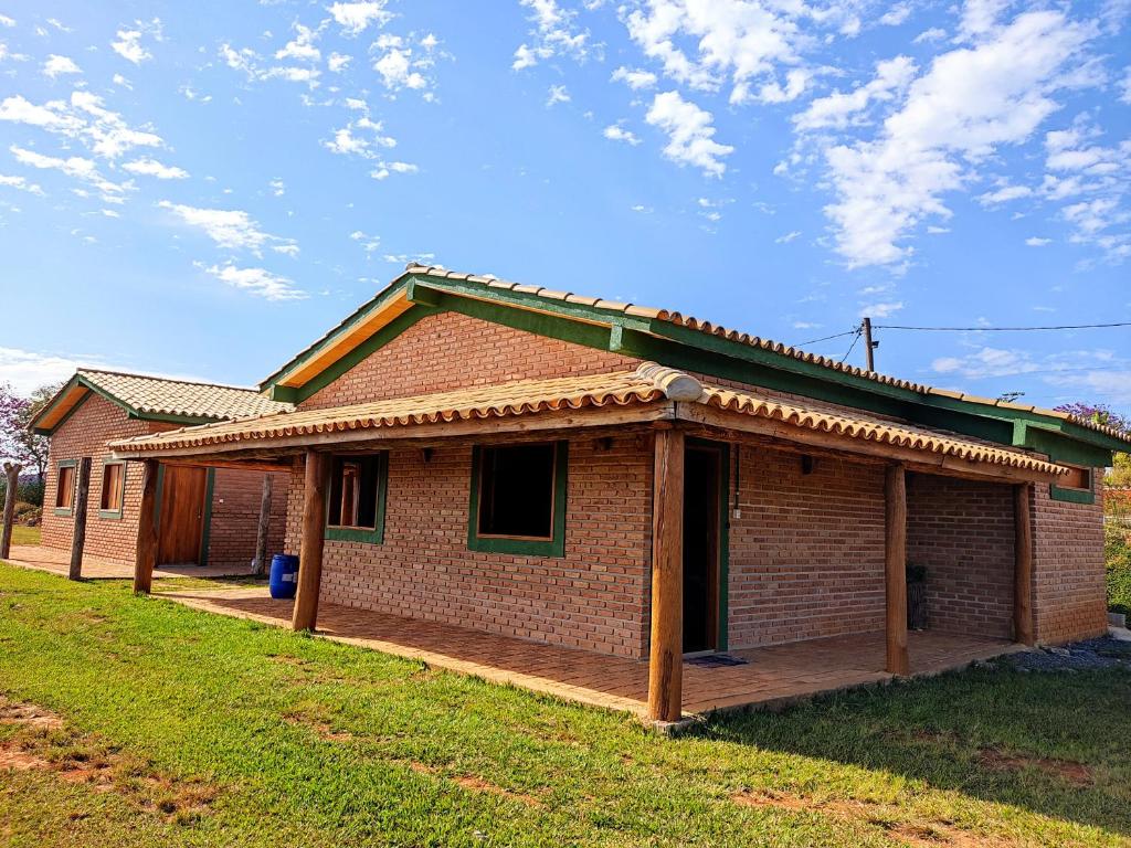 une maison en briques avec une terrasse couverte sur une pelouse dans l'établissement Pousada do Chicó, à São Roque de Minas