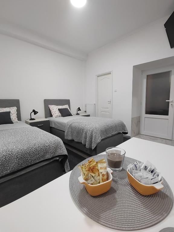 Zimmer mit 2 Betten und einem Tablett mit Essen auf dem Tisch in der Unterkunft Apartman Centar Ivanjica in Ivanjica
