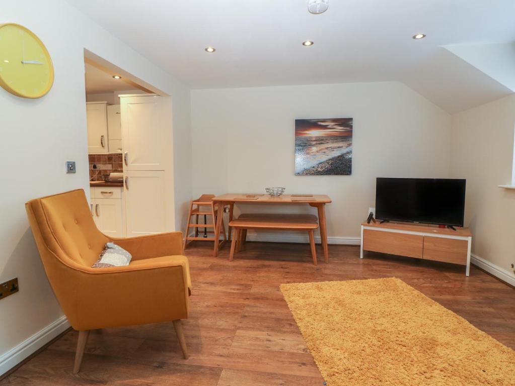 a living room with a chair and a tv and a table at Y Enciliad in Rhosneigr