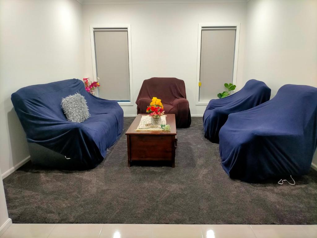 a room with two blue chairs and a table at Maha Melton Homestay in Melton South