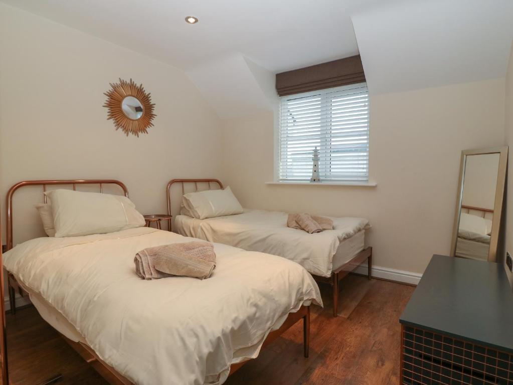 two beds in a room with a mirror on the wall at Y Enciliad in Rhosneigr