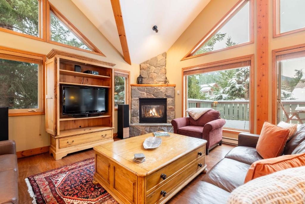 a living room with a fireplace and a tv at Spruce Grove Chalet by Outpost Whistler in Whistler